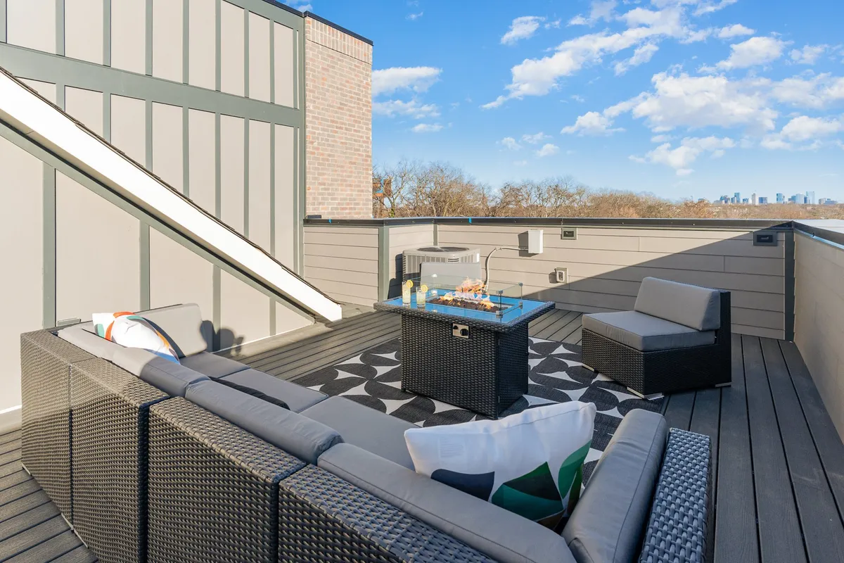 This image captures a stylish rooftop seating area, complete with a coffee table and modern chairs, all set against a backdrop of the Nashville city skyline. The space is designed for socializing and relaxation, with open sky above, suggesting a perfect spot for sunset gatherings or evening drinks beneath the stars.